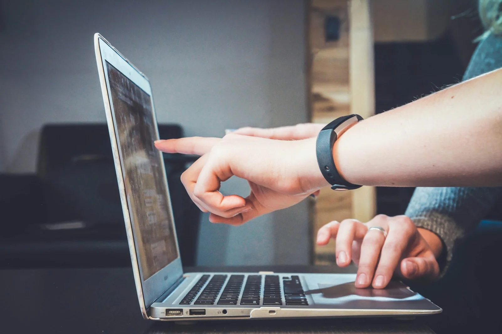 Hands pointing at a laptop during collaborative work